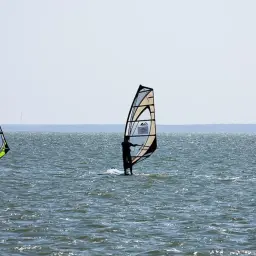 Trzech windsurferów na falach. Idealne miejsce, gdzie na windsurfing w Polsce.