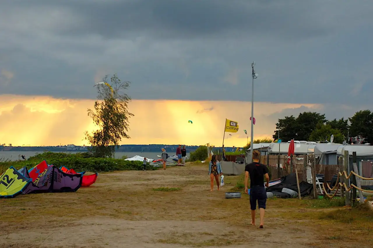 Dziewczyny które kochają kitesurfing, przygotowują sprzęt na plaży. Słońce przebija się przez chmury, tworząc magiczny widok.