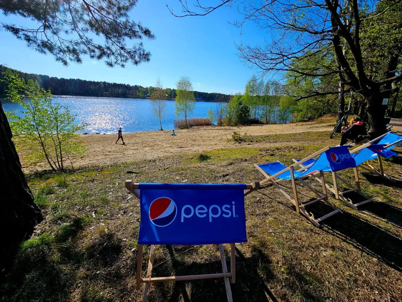 Słoneczny dzień nad dużym jeziorem w Turawie. Leżaki z logo Pepsi czekają na plaży w turawa camp camper park.